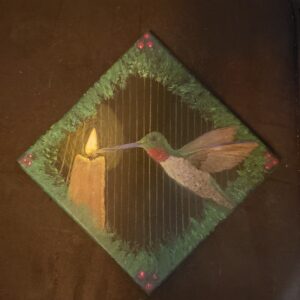 a small black canvas turned sideways to be diamond shaped, on it via neaon and metallic watercolours is a rubzthroated hummingbird with itäs beak touching the flame of a candle, behind is thin metal bars. around the border is red berries at each corner and on all around green foliage.