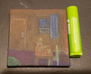 a  small canvas only slightly taller than a tube of chapstick, depicts the inside of a treehouse with a table, chair, rug, door, window, curtains. there's a candle, papers, writing instrument, and book on the table, a key hangs on the wall. out side the window is a railing and darkening bit of sky