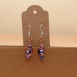 A pair of pearl earrings with copper coloured aluminum wire wrapped around and forming a loop that connects to fishhook earrings.