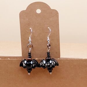 A product photo of a pair of earrings, each of a plastic bat, one of which has eyes, and a few beeds, connected to fishhook findings